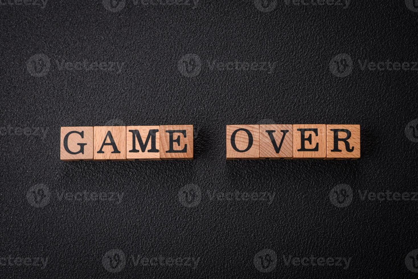 The inscription game over on wooden cubes on a dark concrete background photo