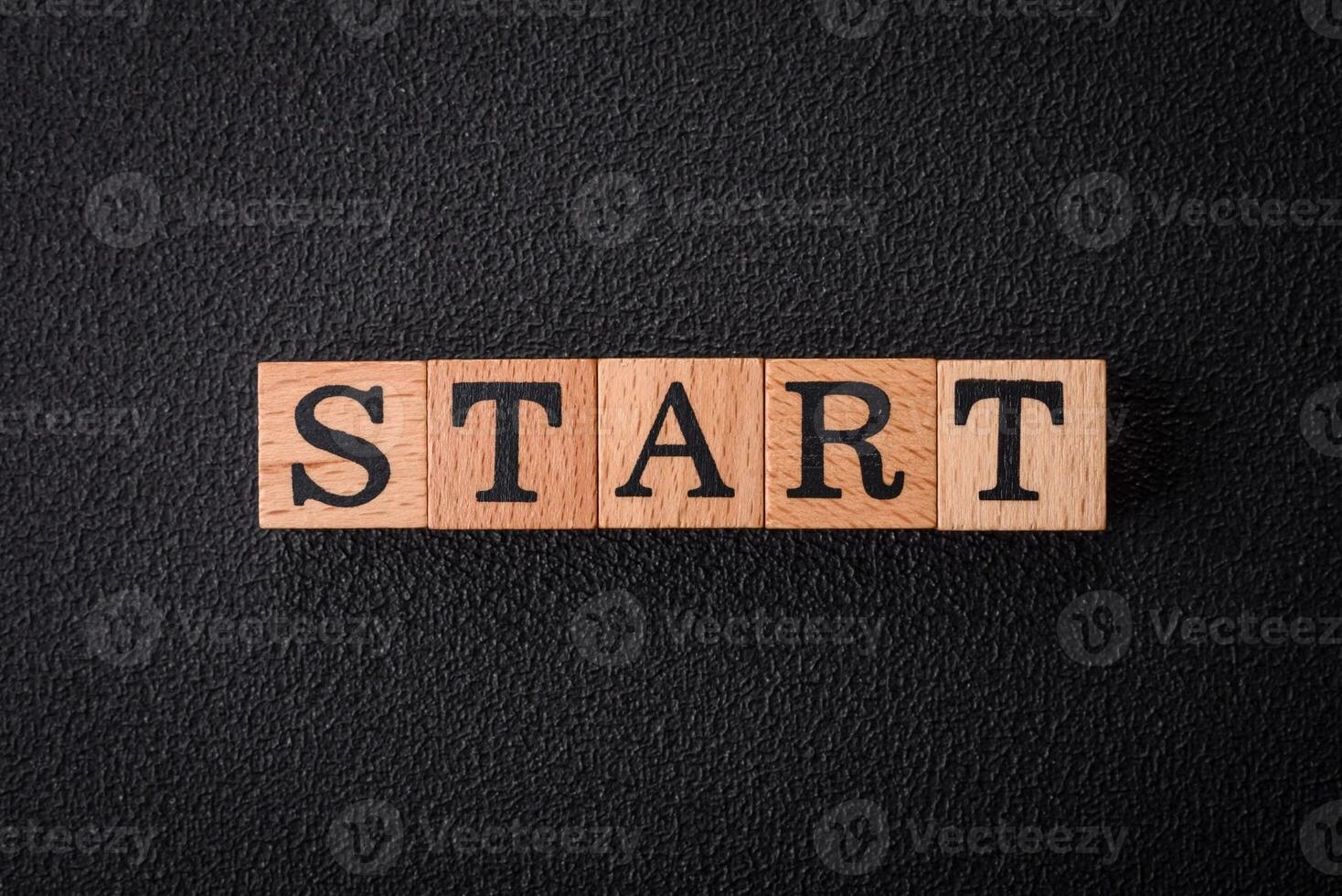 The inscription start on wooden cubes on a dark concrete background photo