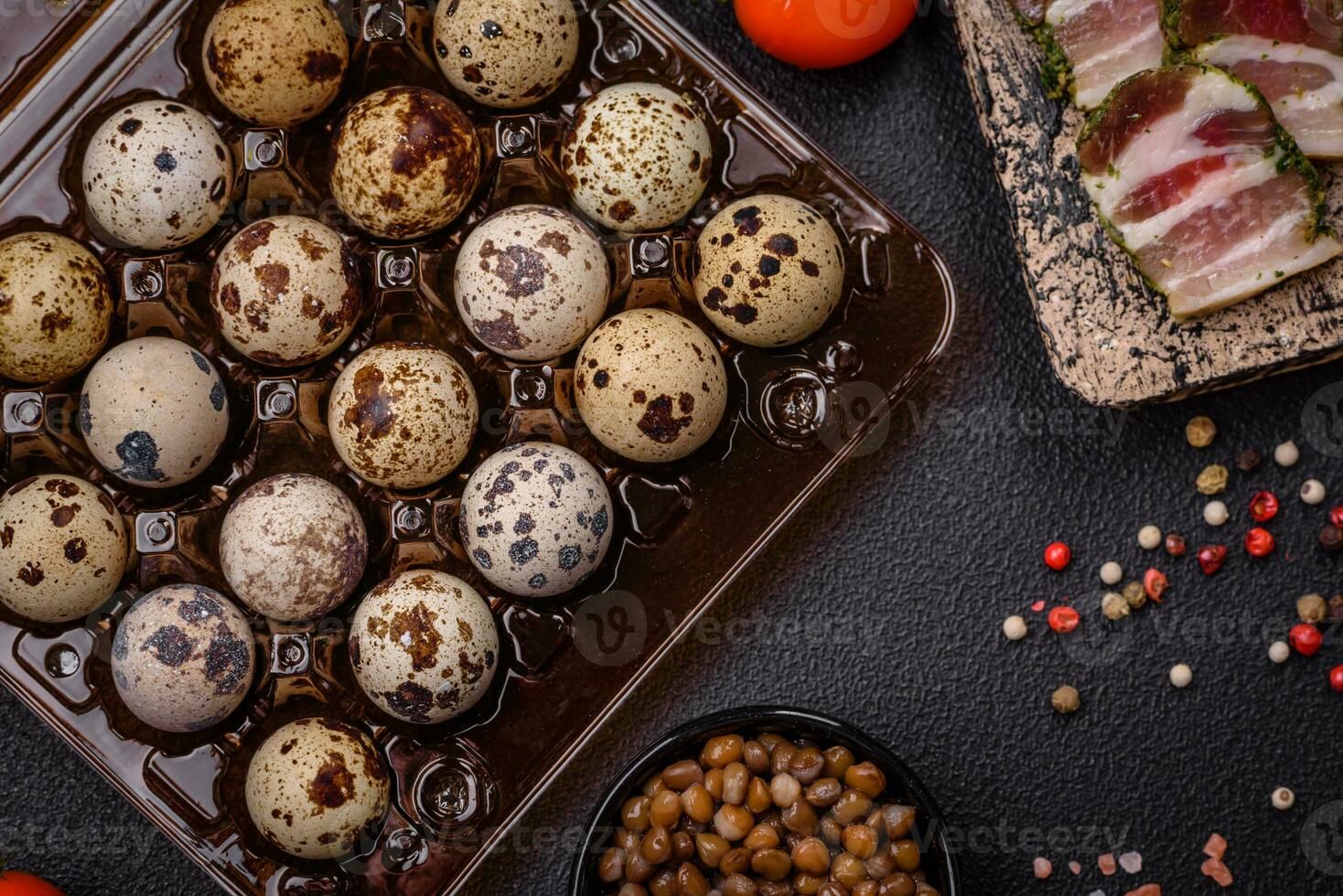 Raw quail eggs in a plastic box on a dark concrete background photo