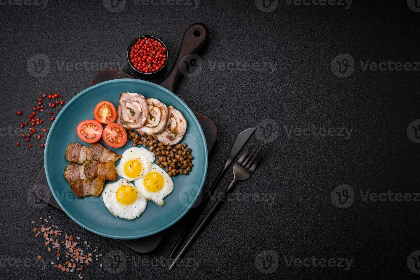 Delicious nutritious breakfast of fried quail eggs, bacon, legumes and cherry tomatoes photo