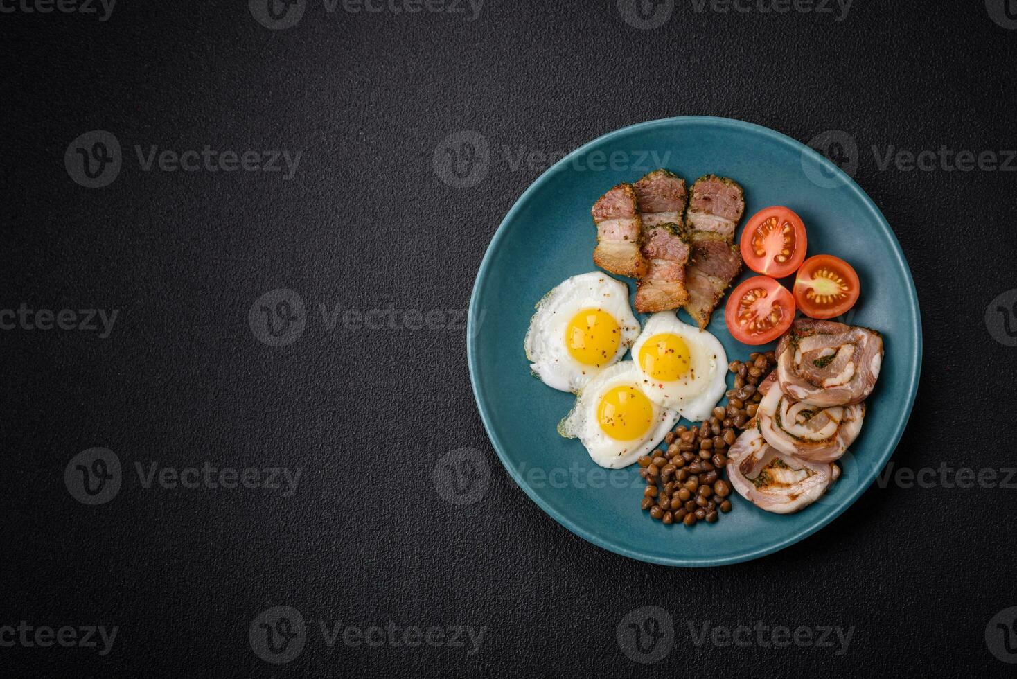 Delicious nutritious breakfast of fried quail eggs, bacon, legumes and cherry tomatoes photo