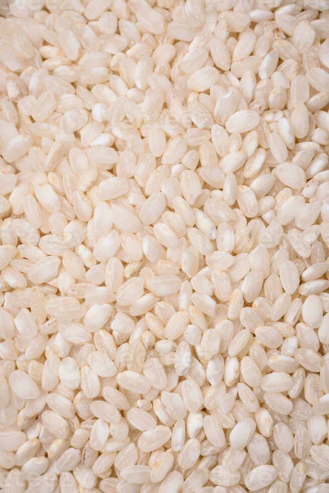 White uncooked rice in a round ceramic bowl on a dark concrete background photo