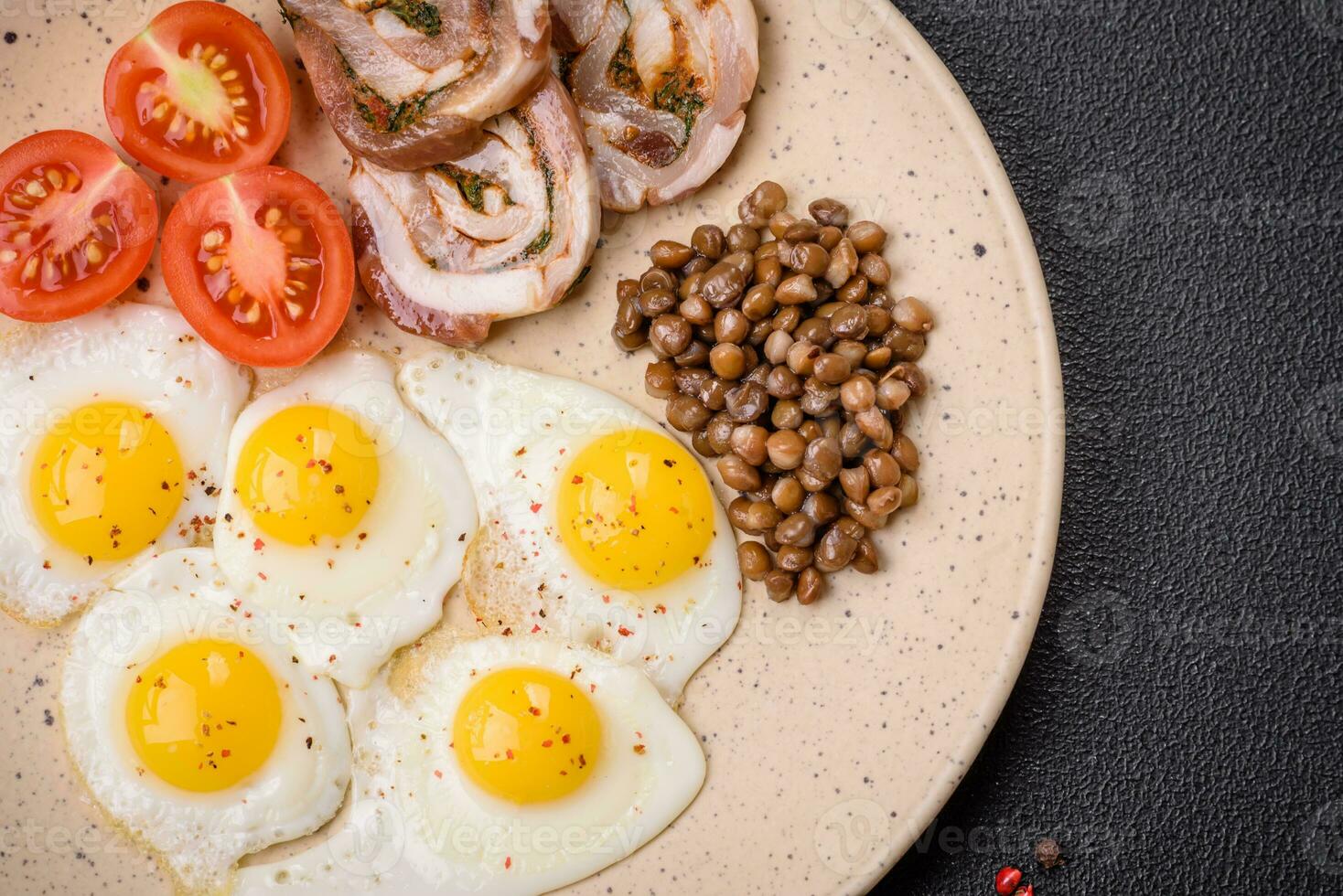 Delicious nutritious breakfast of fried quail eggs, bacon, legumes and cherry tomatoes photo