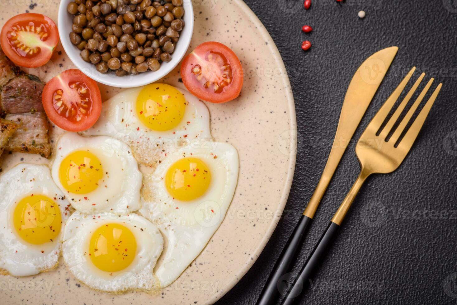 Delicious nutritious breakfast of fried quail eggs, bacon, legumes and cherry tomatoes photo