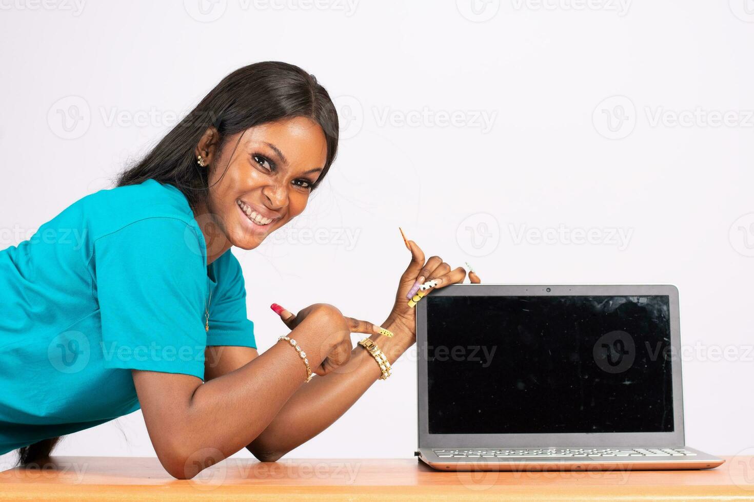 beautiful young black woman pointing to her laptop screen that is blank photo