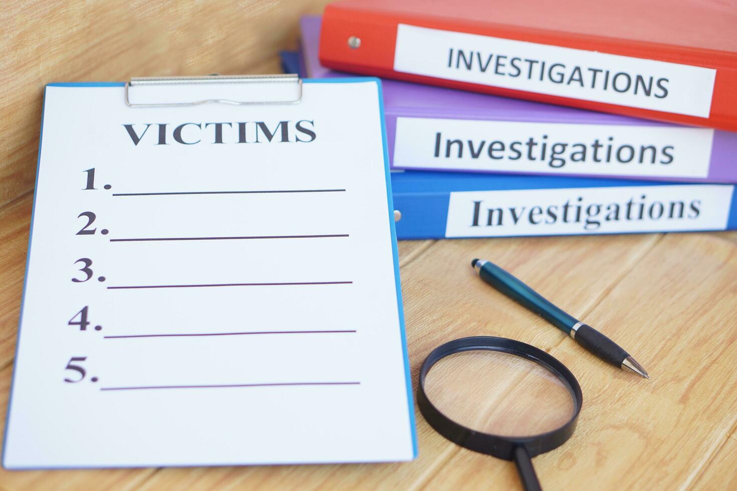 Investigation folders and victims list paper notepad clipboard. Magnifying glass and pen. Concept, crime. Analyzing criminal investigation. photo