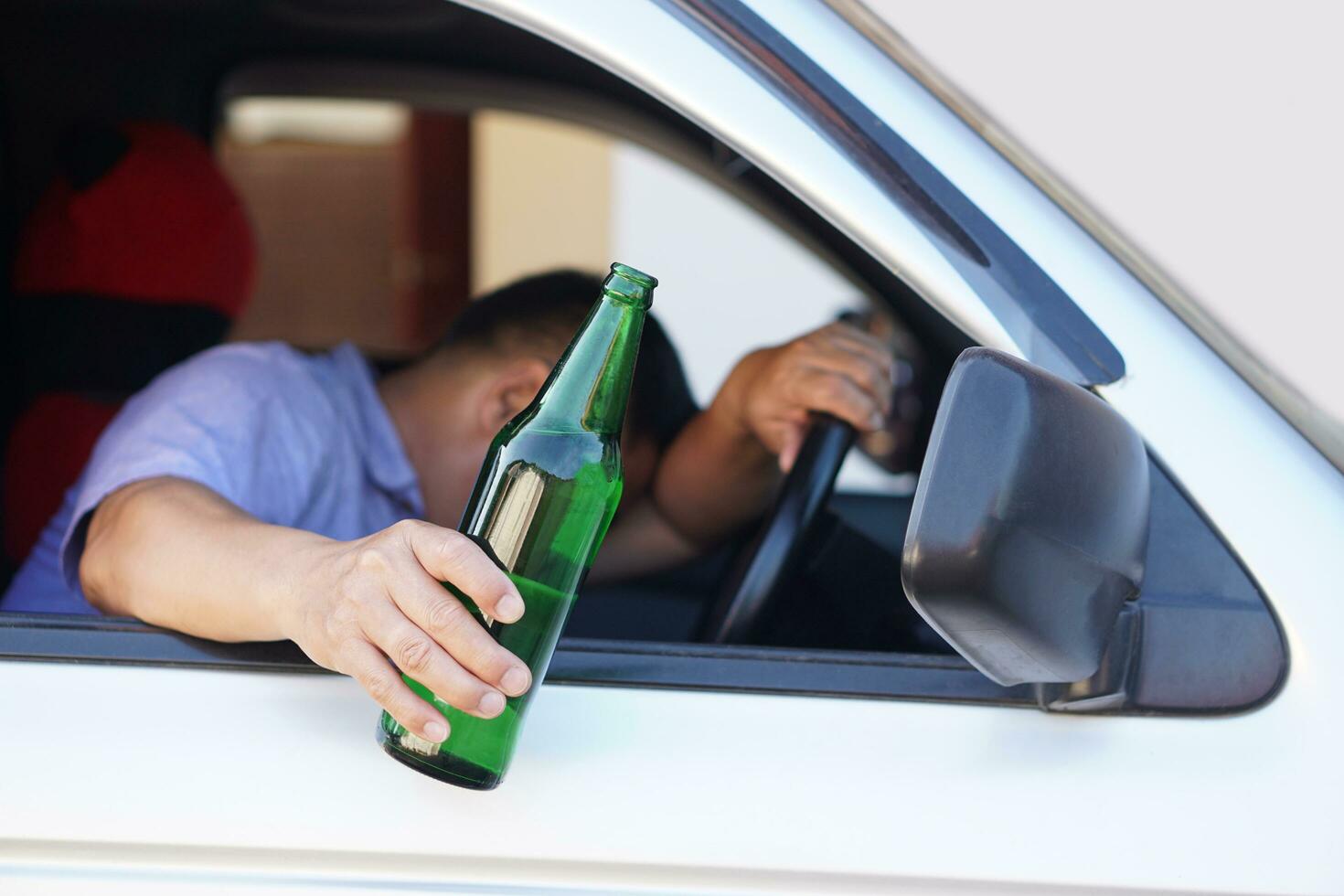 Drunk man holds beer bottle in car. Concept, Stop driving while drinking alcohol beverage or whiskey campaign. Illegal and dangerous to drive vehicle that leads to accident photo