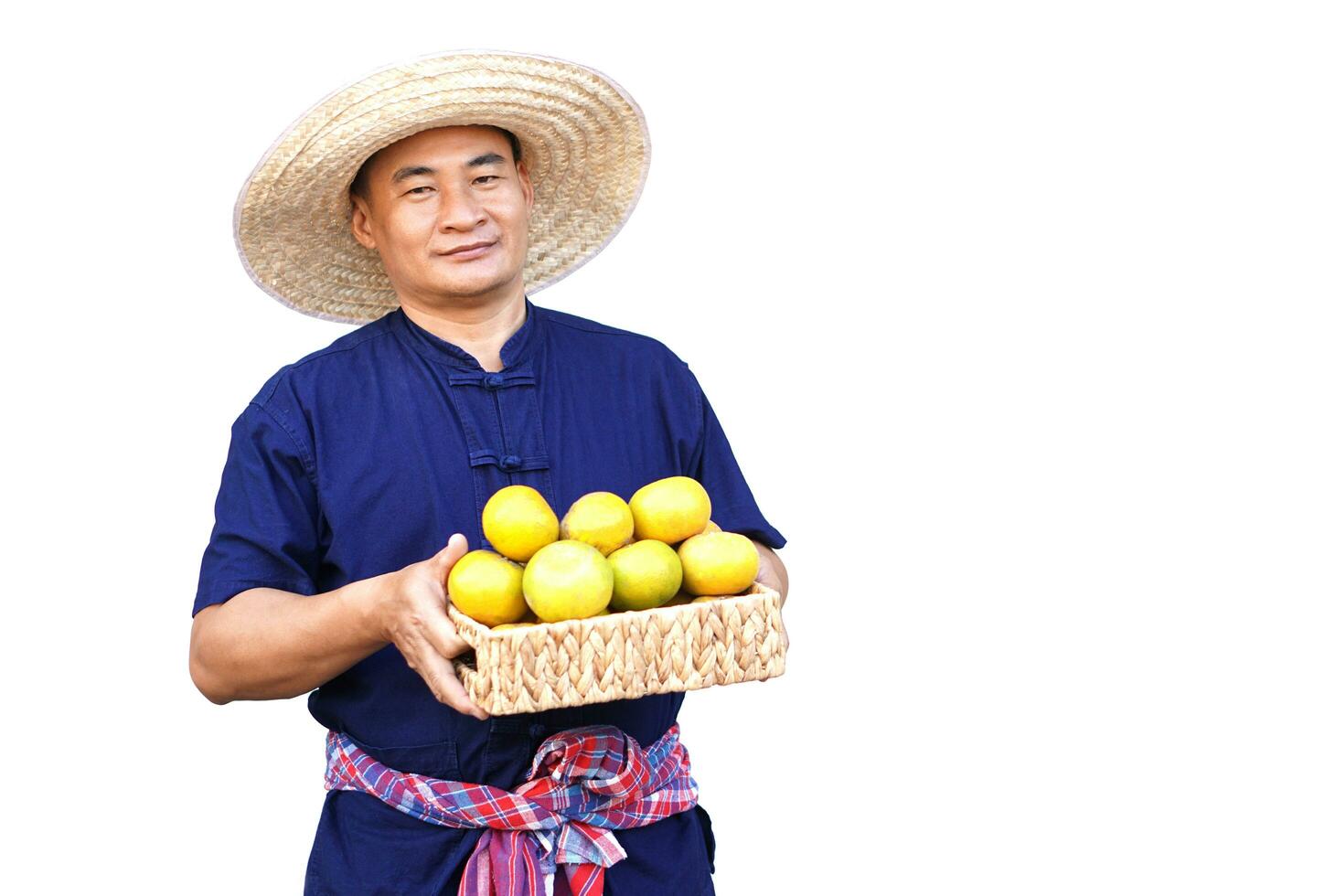 Handsome Asian man farmer wears hat, blue shirt, holds basket of organic orange fruits, make hand to present, isolated on white background. Concept, Agriculture occupation, produce crops to market. photo