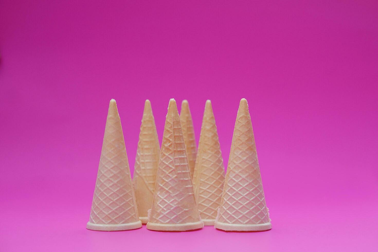 Empty crispy waffle ice cream cones isolated on pink background. Concept, part of pattern of ice creams in cone shape. Snack and dessert. copy space for text. photo