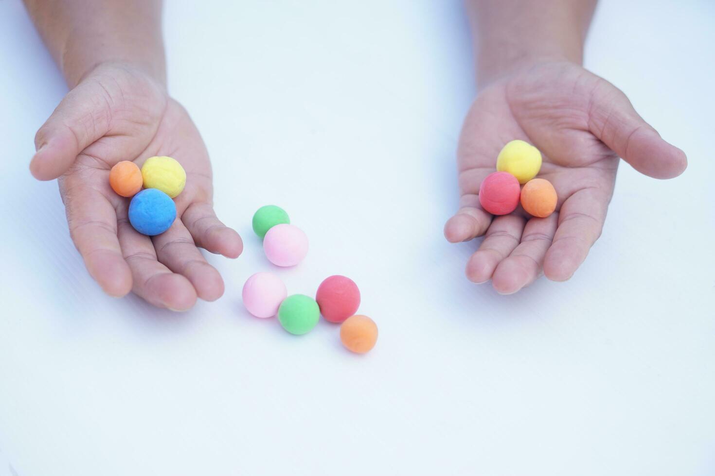 Close up man hands holds small colorful plasticine dough balls. Concept, alzheimer, weak muscle patients recovering activity by sculpting. Make concentration. Develop imagination. photo