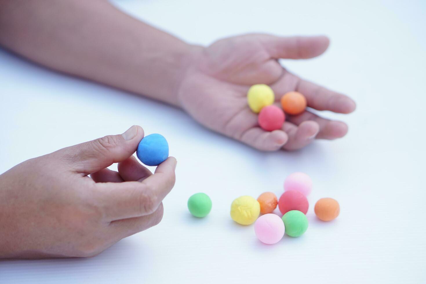 Close up man hands holds small colorful plasticine dough balls. Concept, alzheimer, weak muscle patients recovering activity by sculpting. Make concentration. Develop imagination. photo