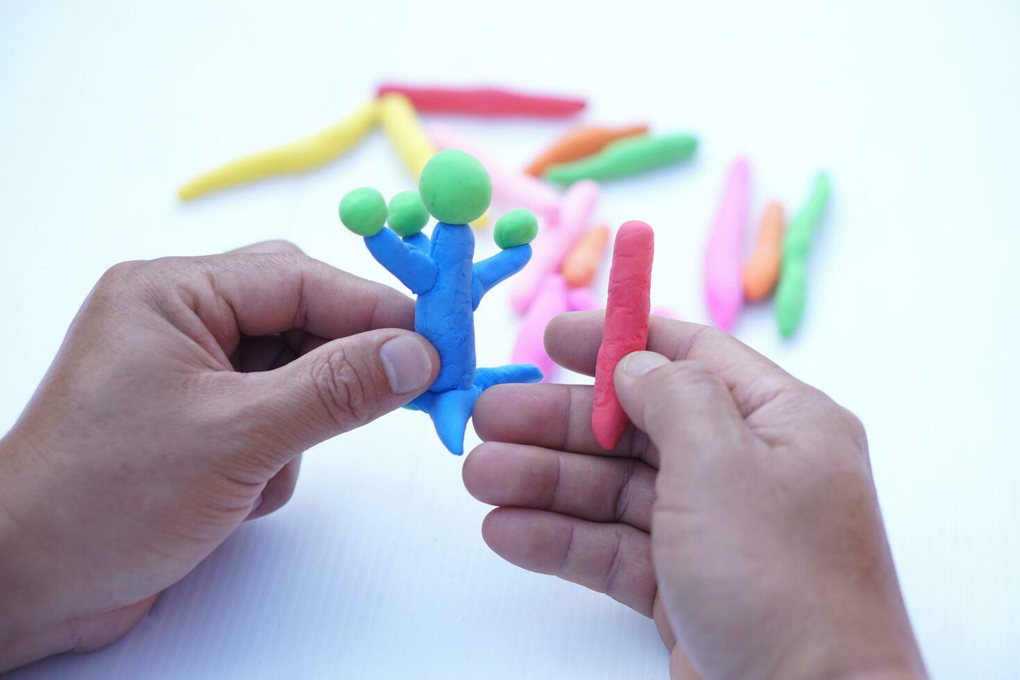 Close up man hands holds small colorful plasticine dough bars to make figures. Concept, alzheimer, weak muscle patients recovering activity by sculpting. Make concentration. Develop imagination. photo