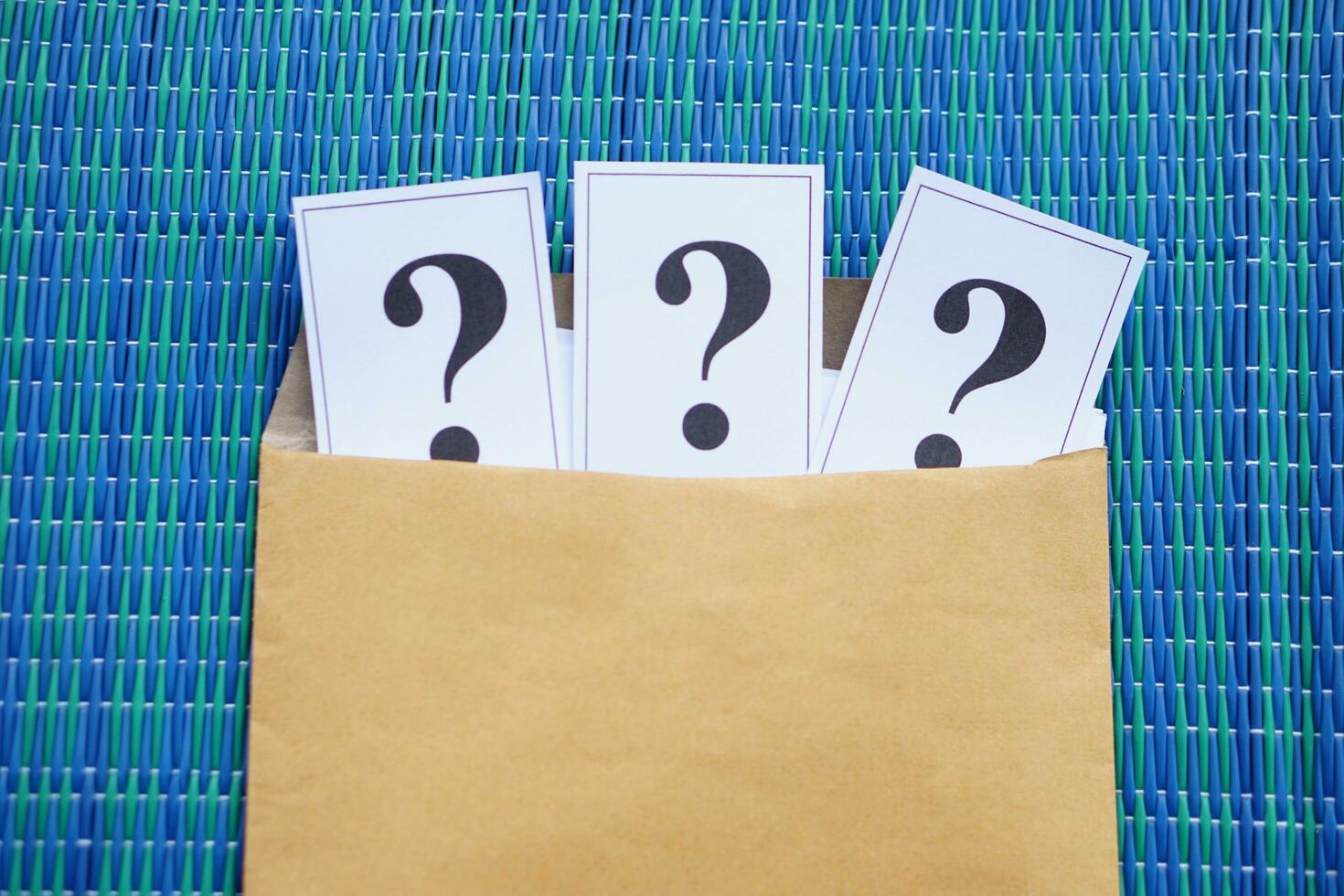 Paper of question marks insert in brown envelope. Concept. Teaching aid. Education materials for doing activity or playing investigation games about find answers. photo