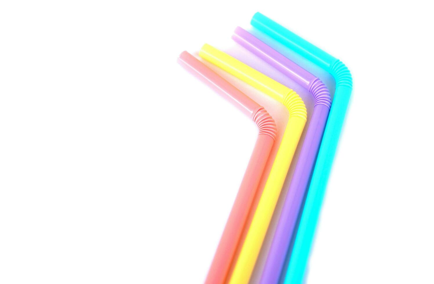 Colorful plastic drinking straws tubes for juice and cocktails, white background. Concept, single use equipment for drinking, but can use for diy crafts for decoration. photo