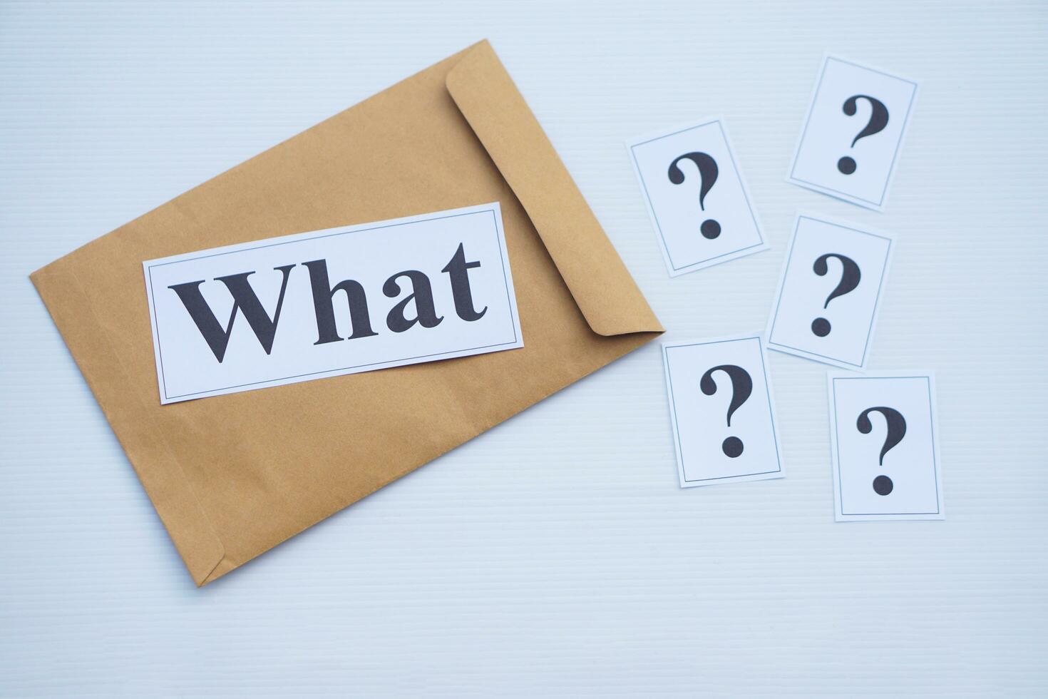 Word cards with question word What on brown envelope and cards of question marks. Concept. Teaching aid. Education materials for teach WH- question. Asking questions. Suspicious symbol to find answer. photo