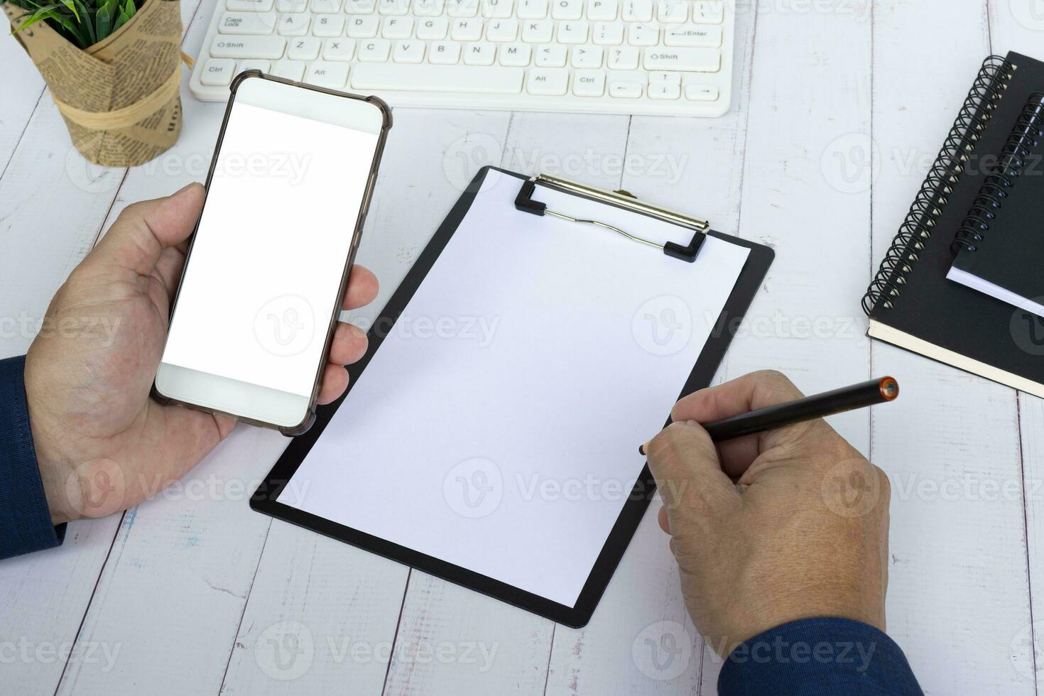 Hand holding a pen and smartphone with copy space. Business concept. photo