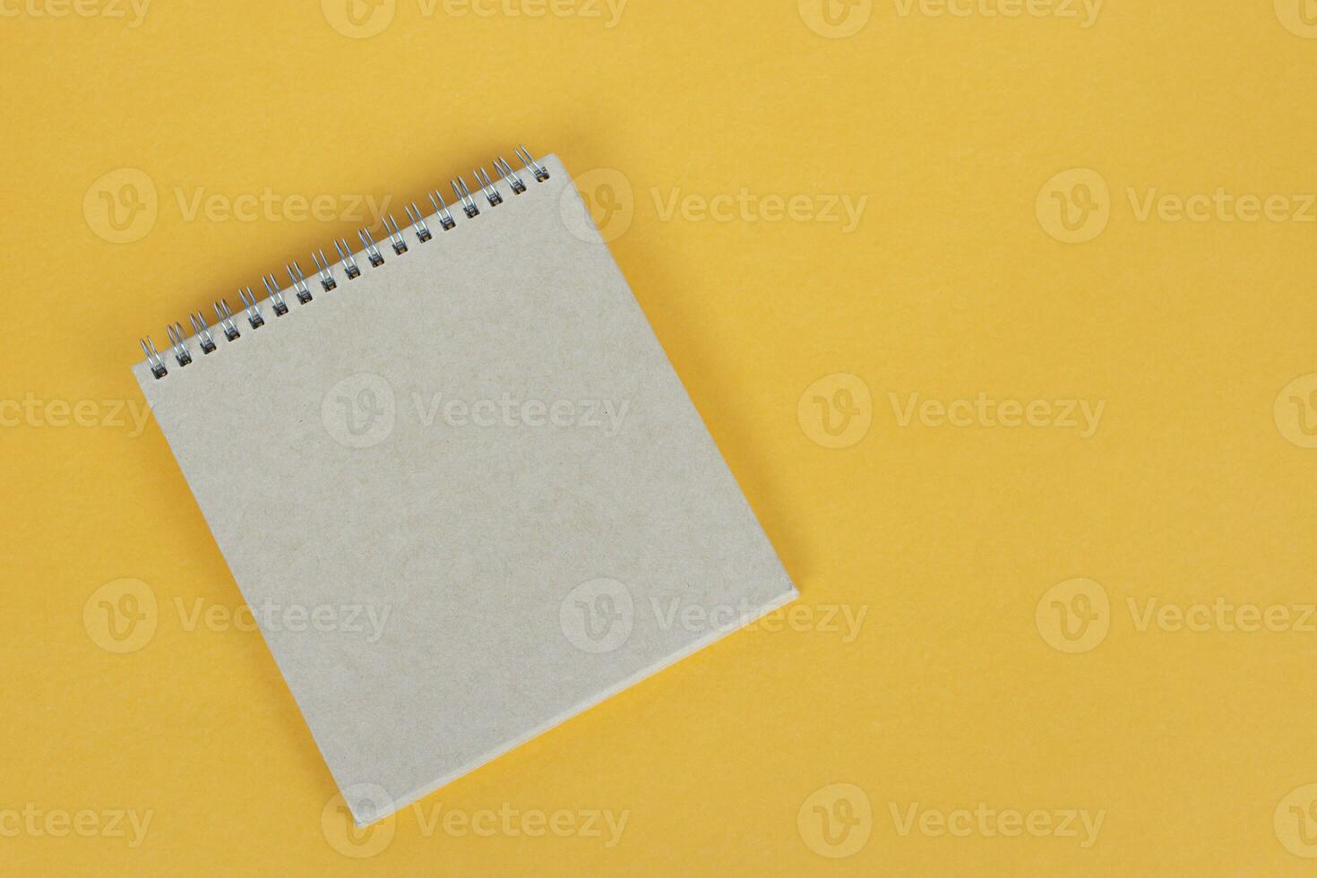 Top view of brown notepad on yellow background. Copy space. photo