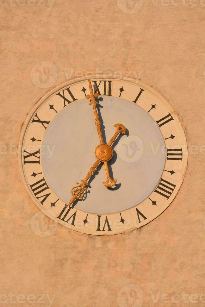 a clock on the side of a building with roman numerals photo