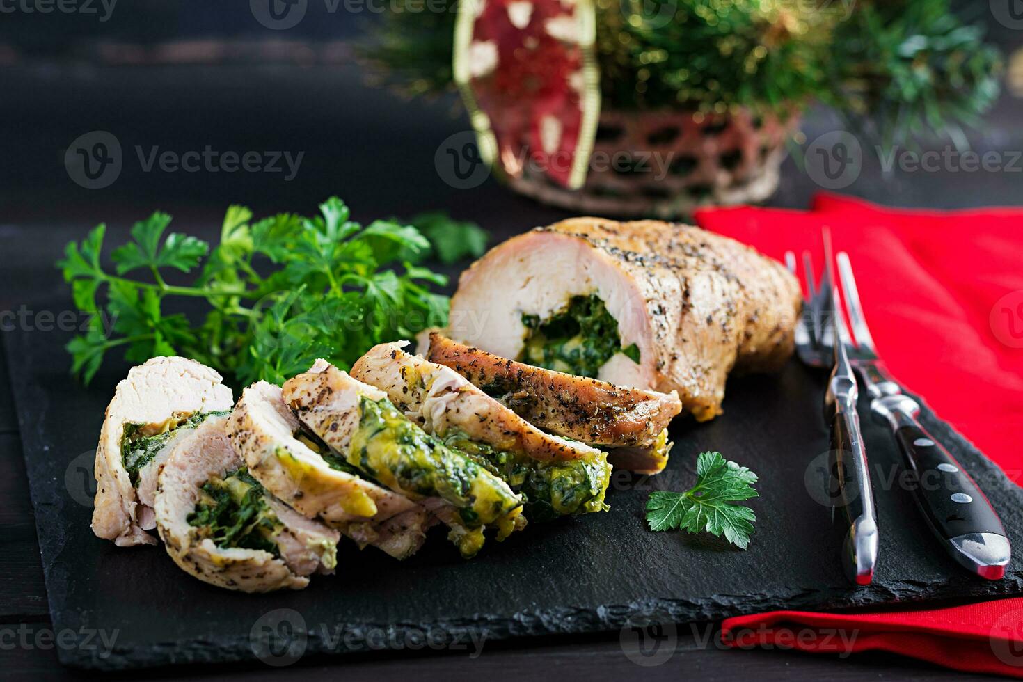 Roasted sliced Christmas roll of turkey with spinach and cheese on dark rustic background.  Festival food. photo