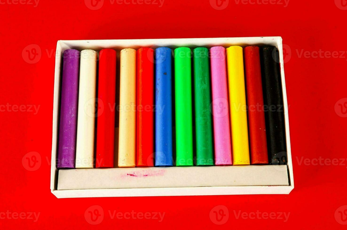 a box of colored crayons on a red background photo