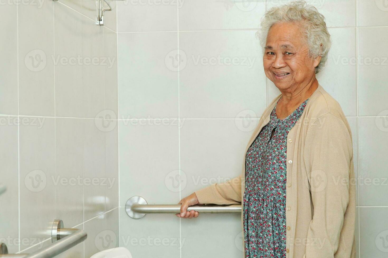 Asian elderly old woman patient use toilet support rail in bathroom, handrail safety grab bar, security in nursing hospital. photo