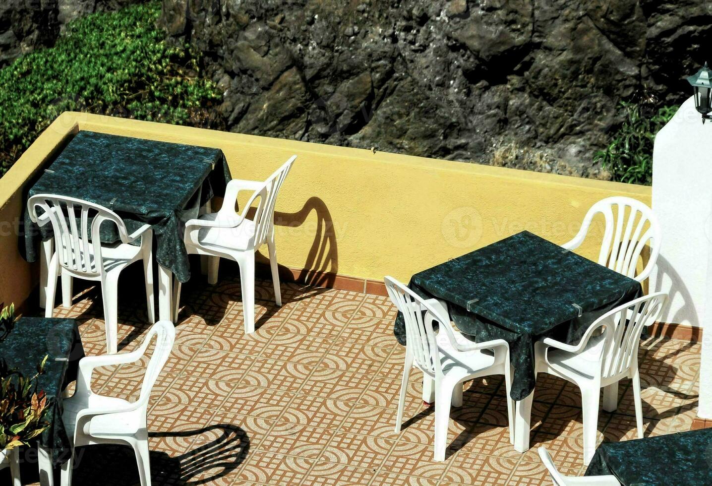 a patio with tables and chairs on the side of a cliff photo