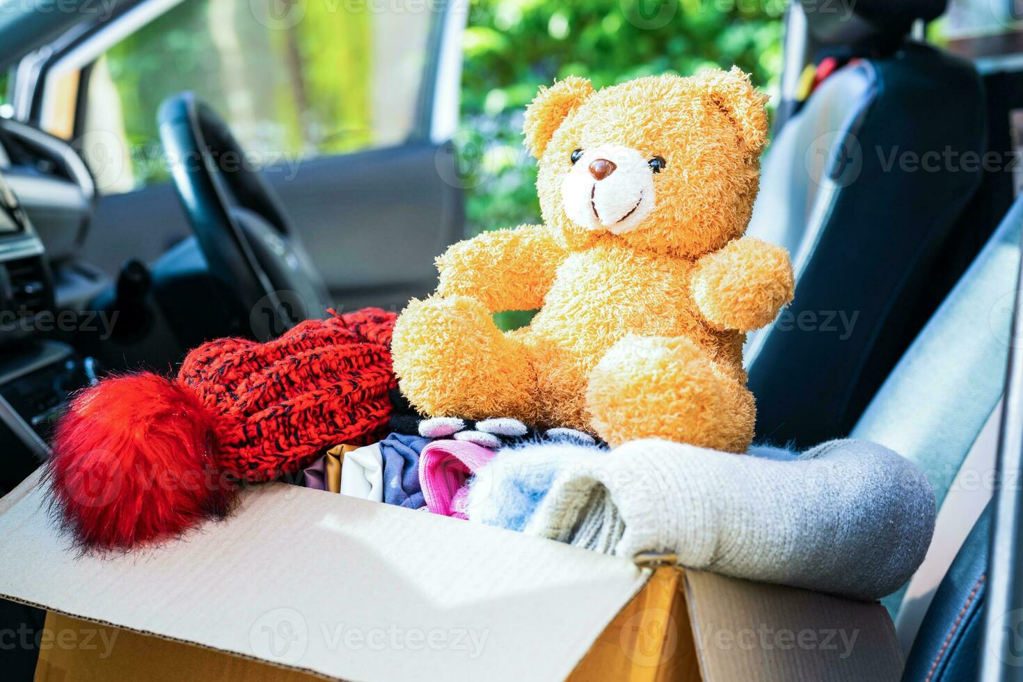 Volunteer provide clothing donation box with used clothes and doll in car to support help for refugee, homeless or poor people in the world. photo