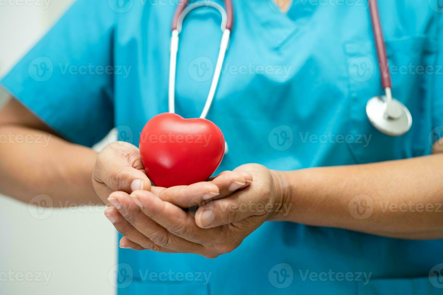 Doctor holding a red heart in hospital ward, healthy strong medical concept. photo