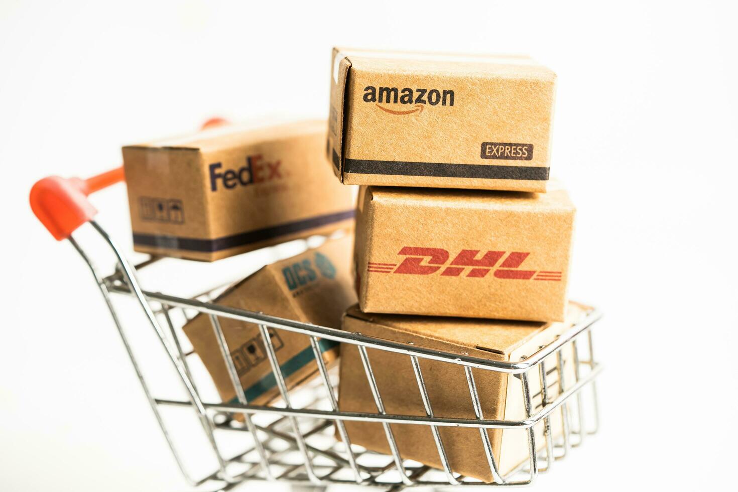 Bangkok, Thailand September 26, 2022 Shopping cart with DHL Amazon and FedEx express packing box, import export online exchange investment business. photo