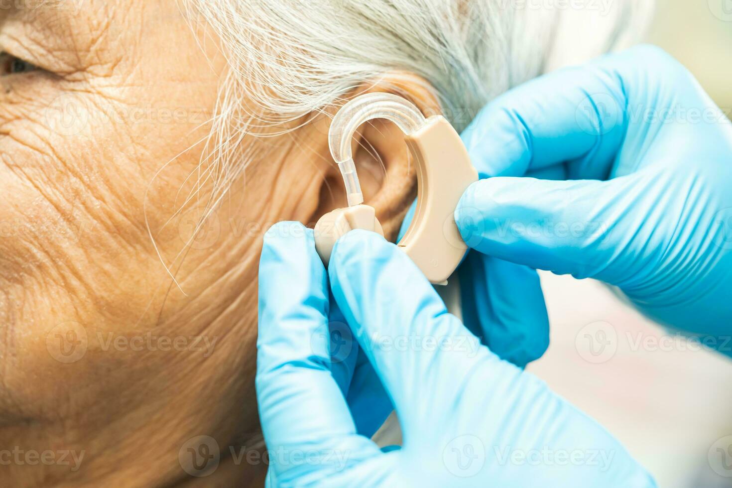 Asian senior woman patient wearing a hearing aid for treating hearing loss problem. photo