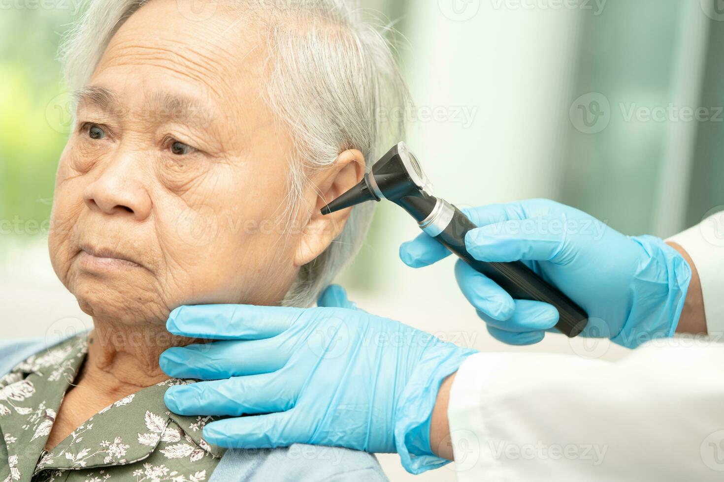 Audiologist or ENT doctor use otoscope checking ear of asian senior woman patient treating hearing loss problem. photo