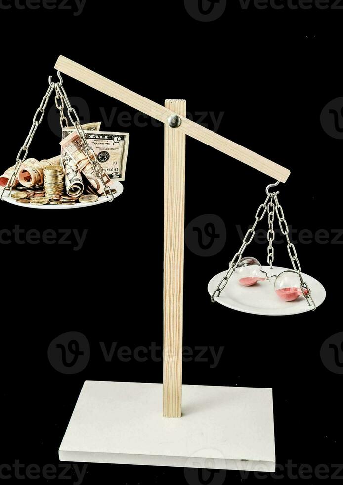 a balance scale with money and an hourglass photo