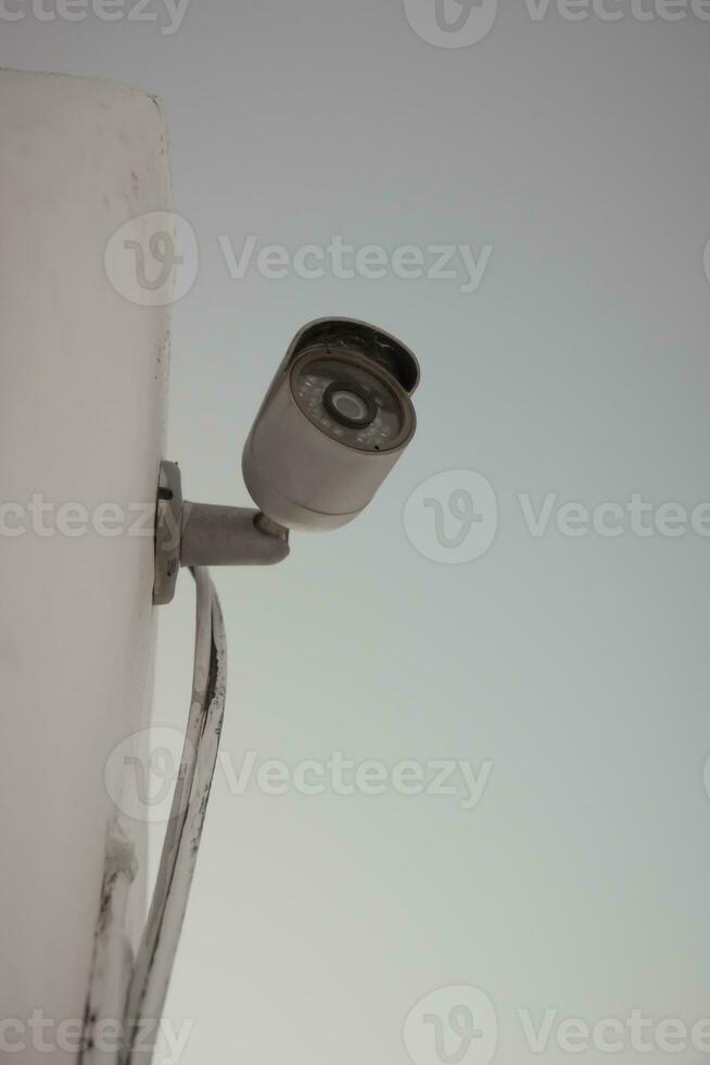 Vertical shot of a domestic security camera mounted against a wall photo