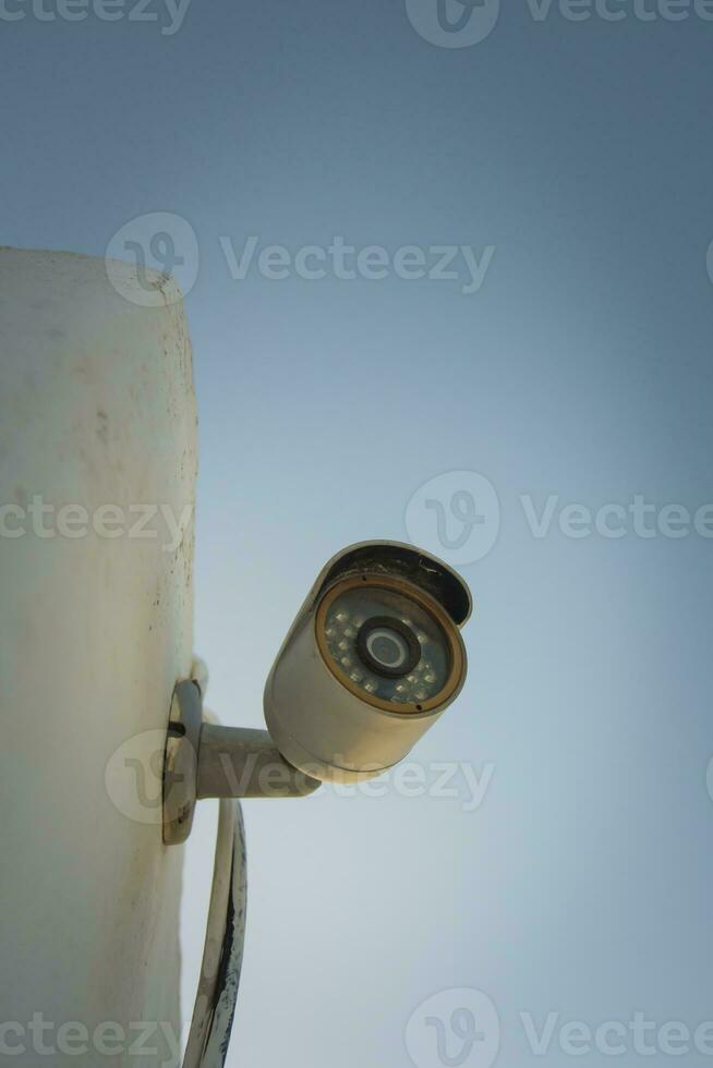 Vertical shot of a domestic security camera mounted against a wall photo