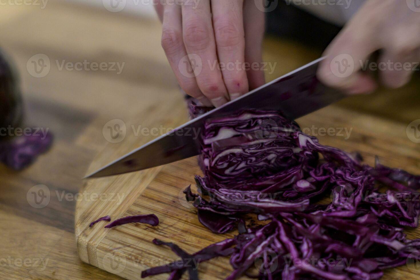 el cortar rojo repollo con un cocina cuchillo en un de madera corte tablero foto