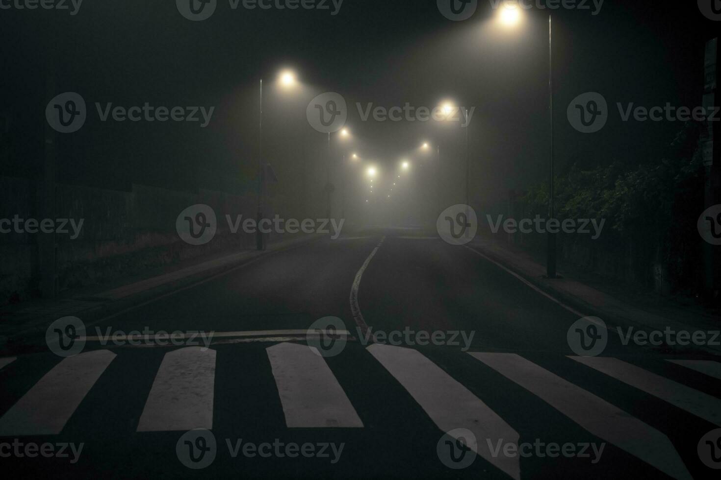 Night shot of a desolate, empty and abandoned city street with streetlights illuminating the road photo