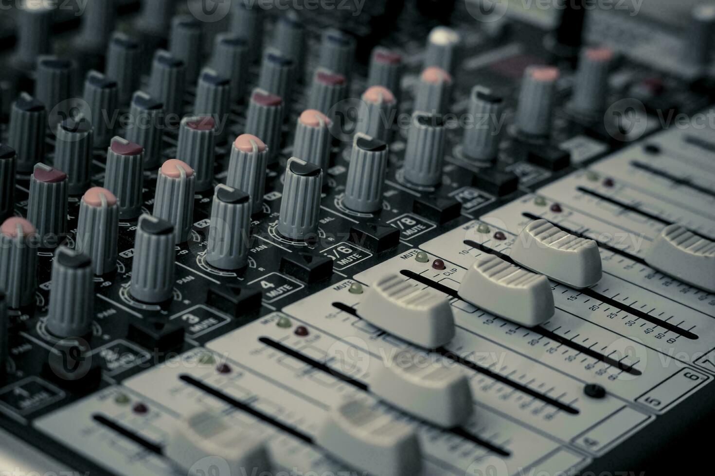 Closeup and detail of audio mixing console with faders and knobs photo