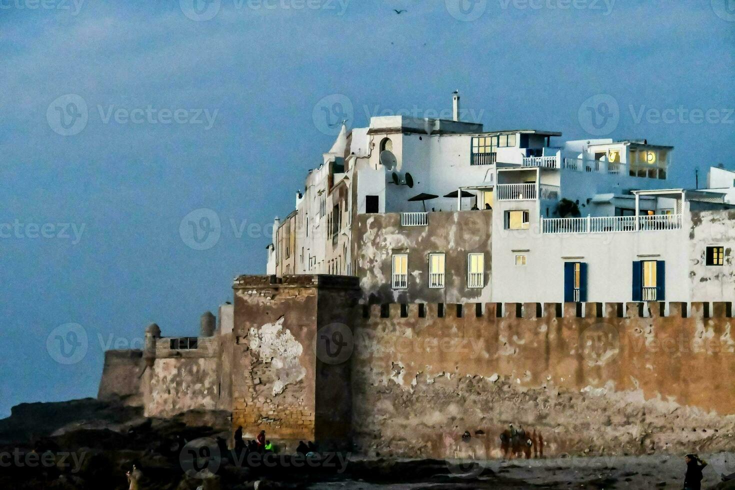 a white building on the beach with blue sky photo