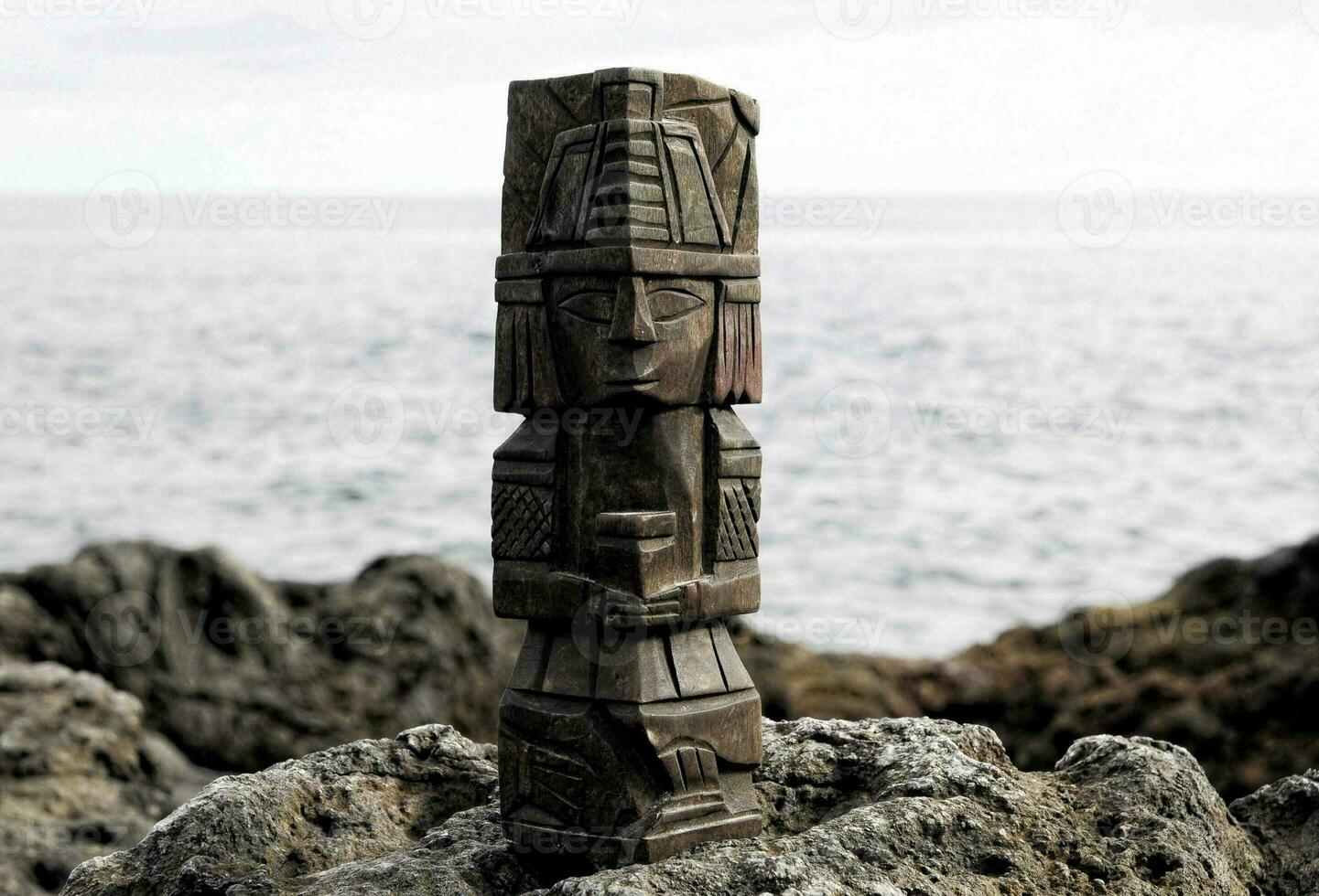 a wooden totem pole on a rock by the ocean photo
