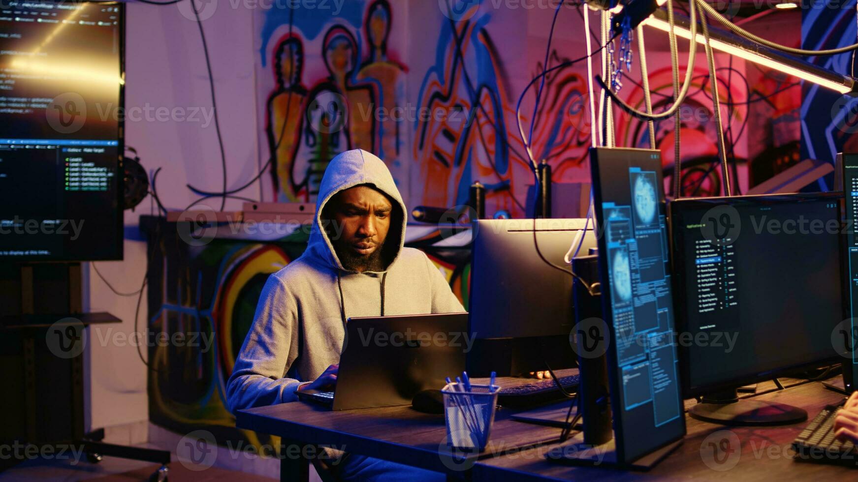 Hacker arriving with laptop in hidden base, deploying viruses on unaware victims computers, stealing sensitive and private information, selling it on darknet black market to highest bidder photo