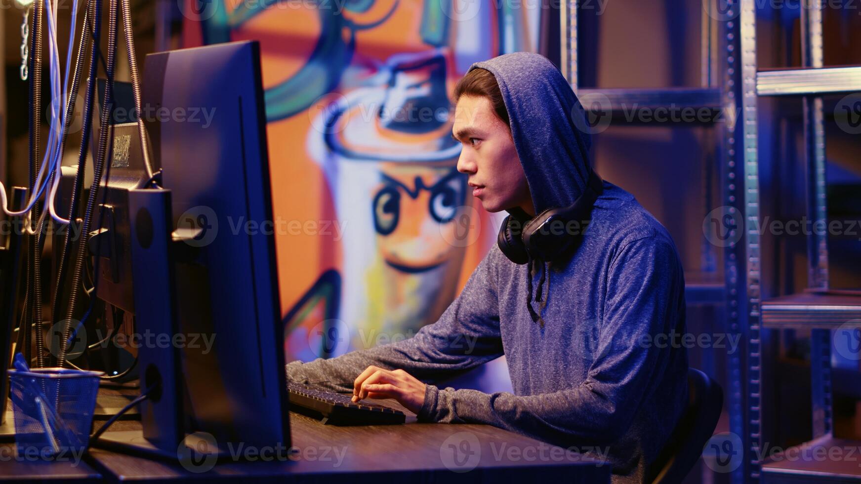 Happy asian hacker in graffiti painted hideout having burst of joy after managing to steal valuable data, using phishing technique that tricks users into revealing sensitive information photo