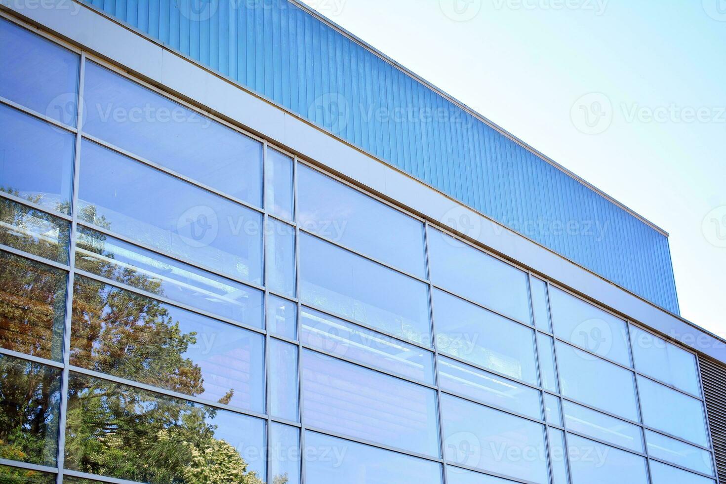 Glass building with transparent facade of the building and blue sky. Structural glass wall reflecting blue sky. Abstract modern architecture fragment. Contemporary architectural background. photo