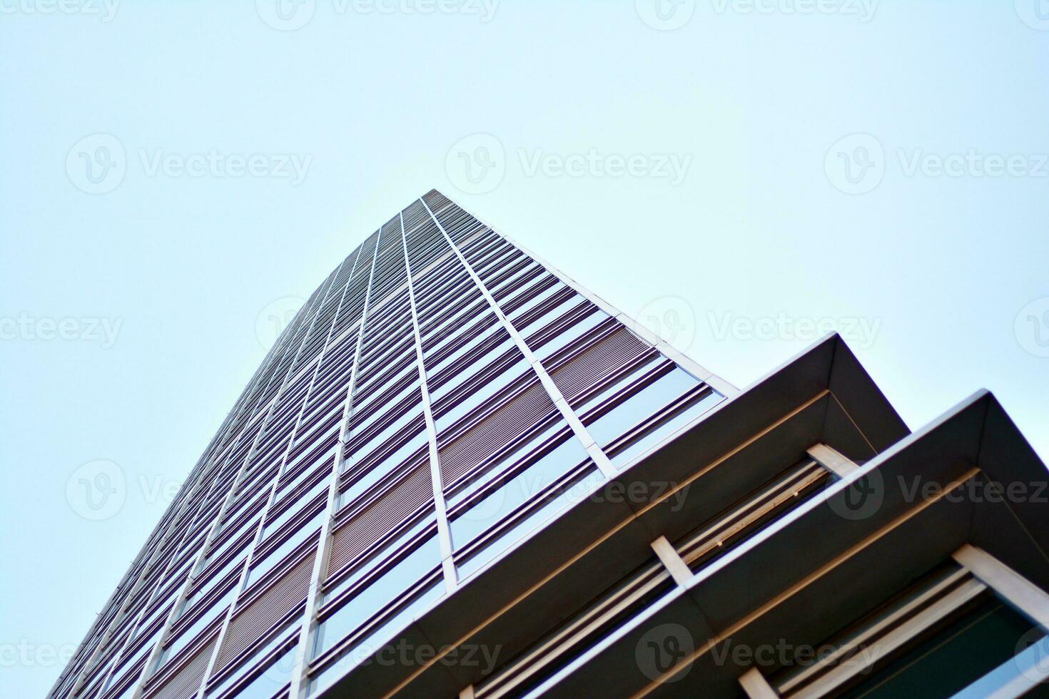 Glass building with transparent facade of the building and blue sky. Structural glass wall reflecting blue sky. Abstract modern architecture fragment. Contemporary architectural background. photo
