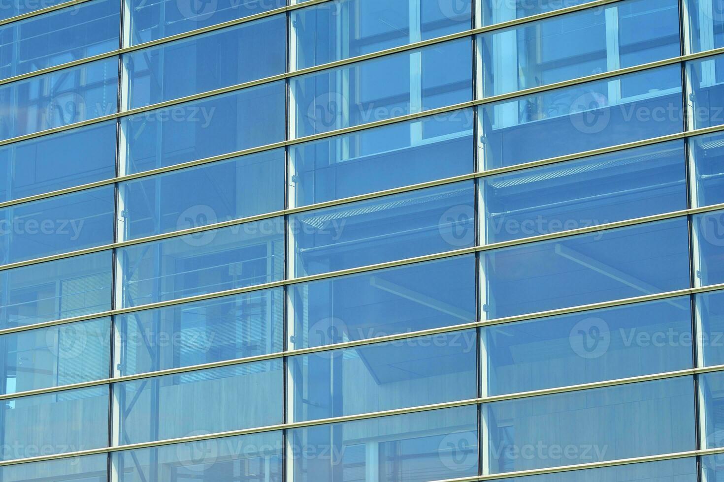 Glass building with transparent facade of the building and blue sky. Structural glass wall reflecting blue sky. Abstract modern architecture fragment. Contemporary architectural background. photo