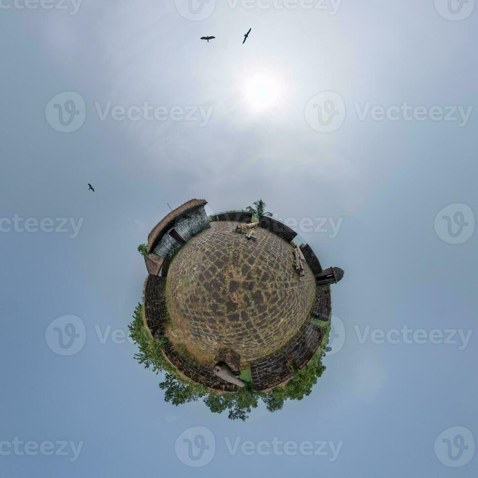 coconut trees in jungle in Indian tropic village on sea shore with fisher boat on little planet in evening sky, transformation of spherical 360 panorama. photo