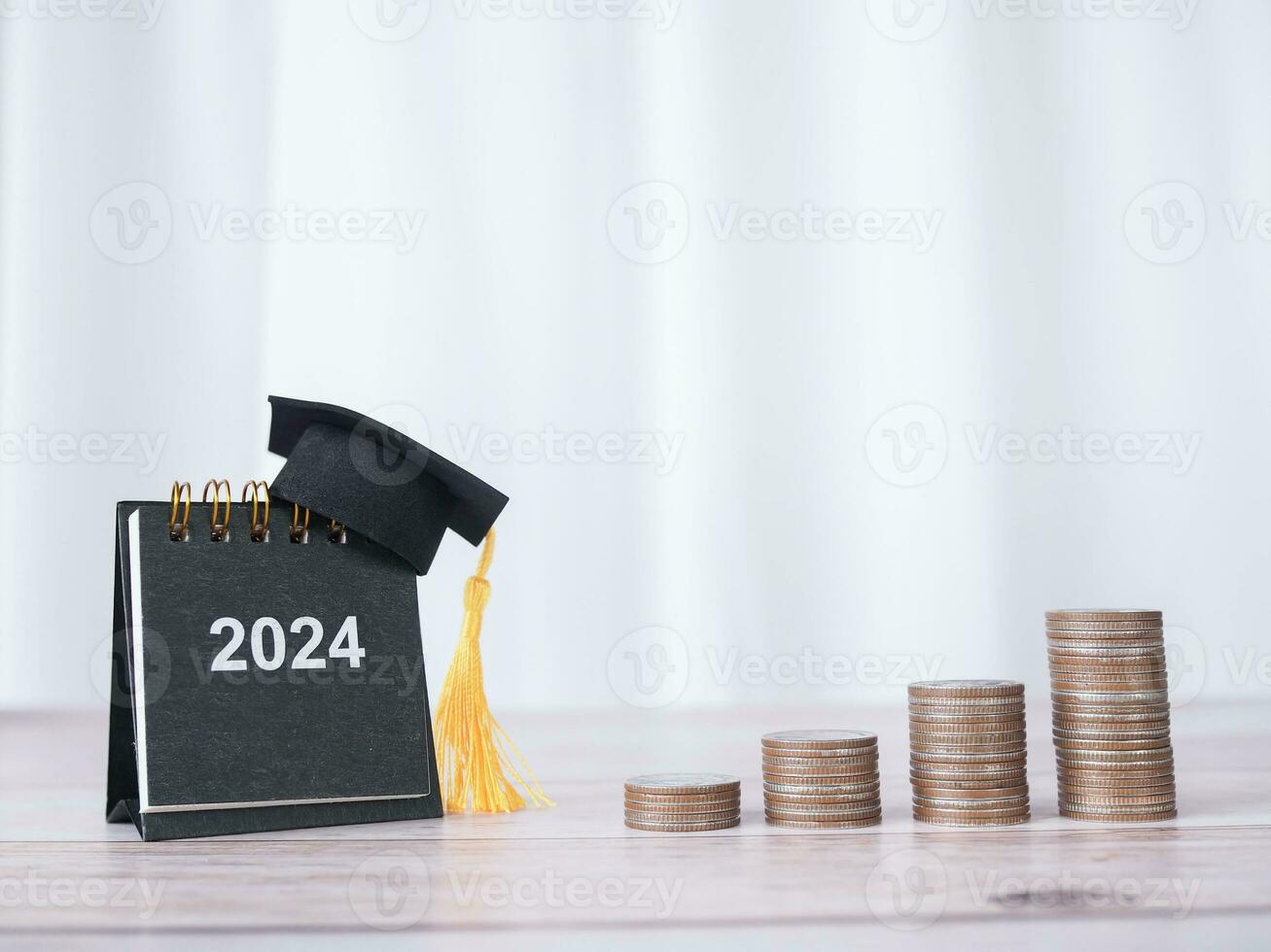 Study goals, 2024 Desk calendar with graduation hat and stack of coins. The concept of saving money for education, student loan, scholarship, tuition fees in New Year 2024 photo