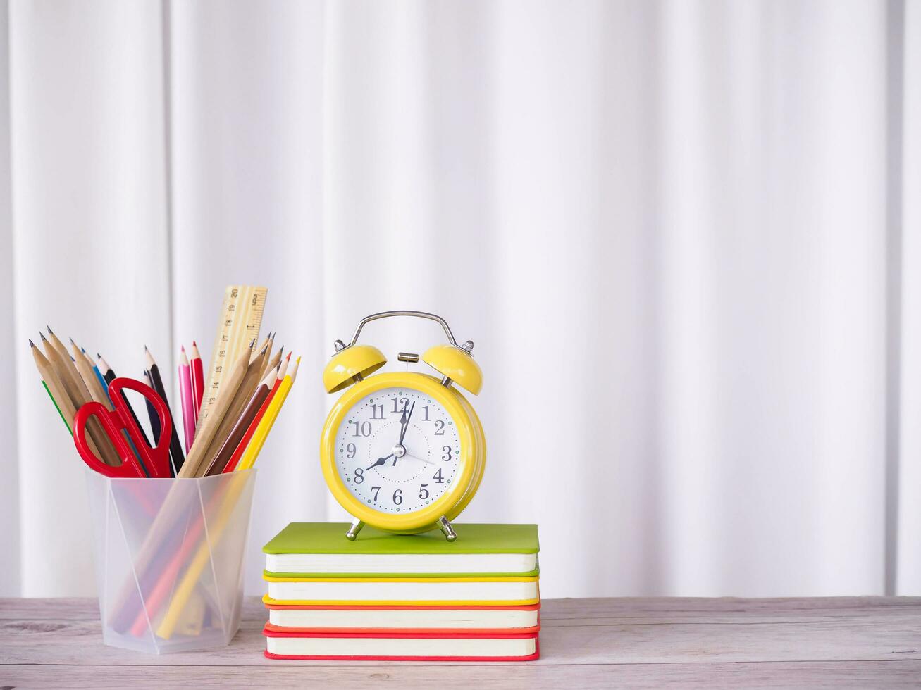 Yellow alarm on hardcover book and colorful stationery. Copy space for text, Office workspace concept. photo