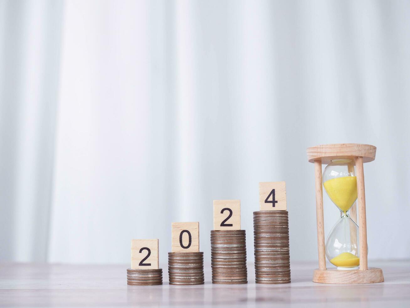 Hourglass and Wooden block with number 2024 on stack of coins. The concept of saving money, Financial, Investment and Business growing in new year 2024. photo