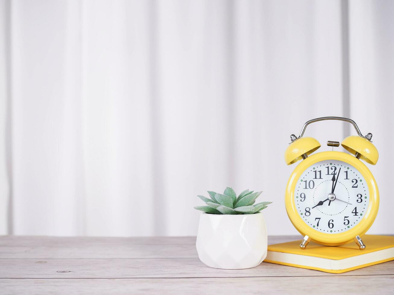 Yellow alarm on hardcover book and cactus with white curtain for background. Copy space for text, Office desk concept. photo