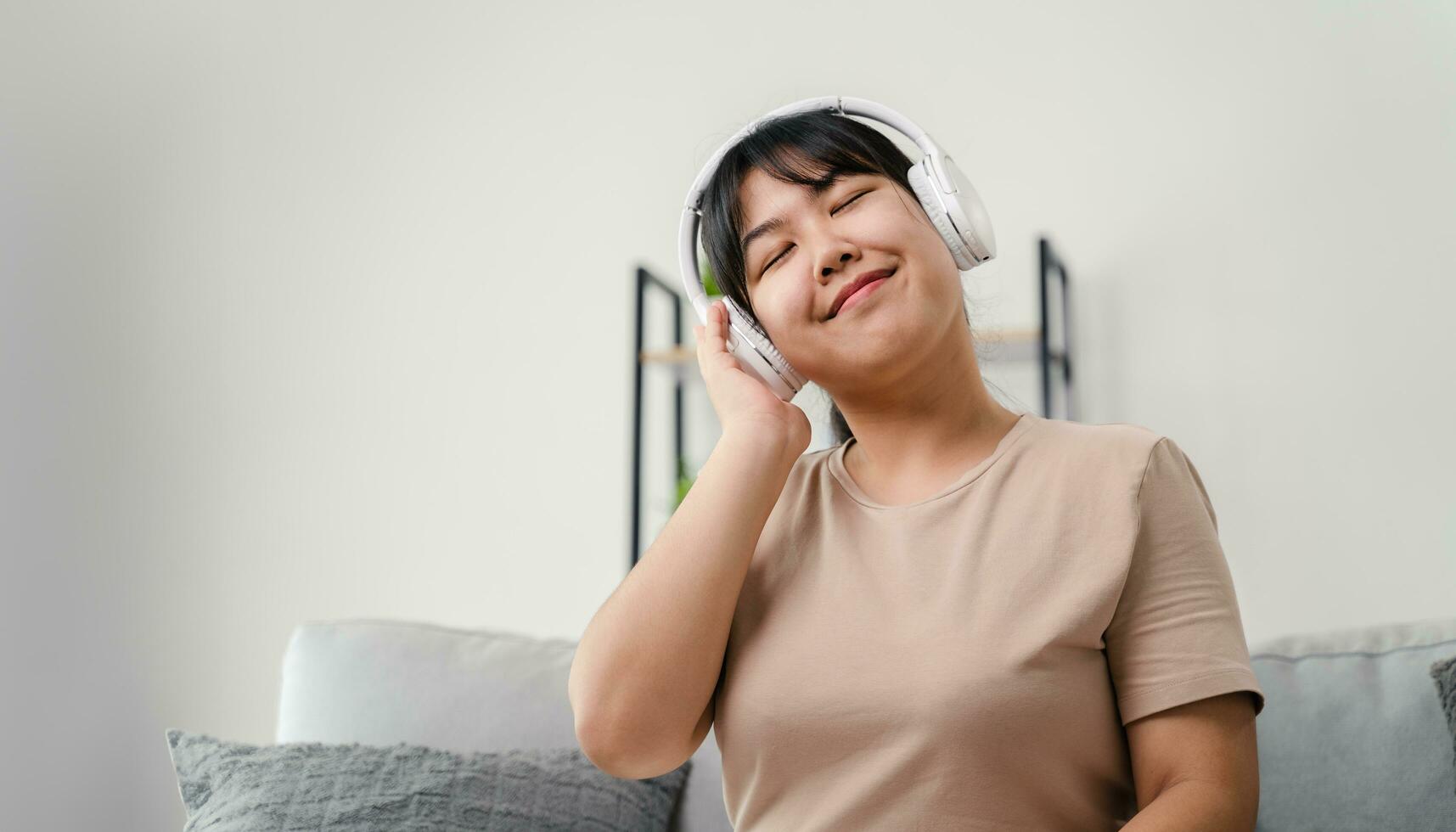 Young woman listening to music with headphone and relaxing while sitting on the sofa at home. photo